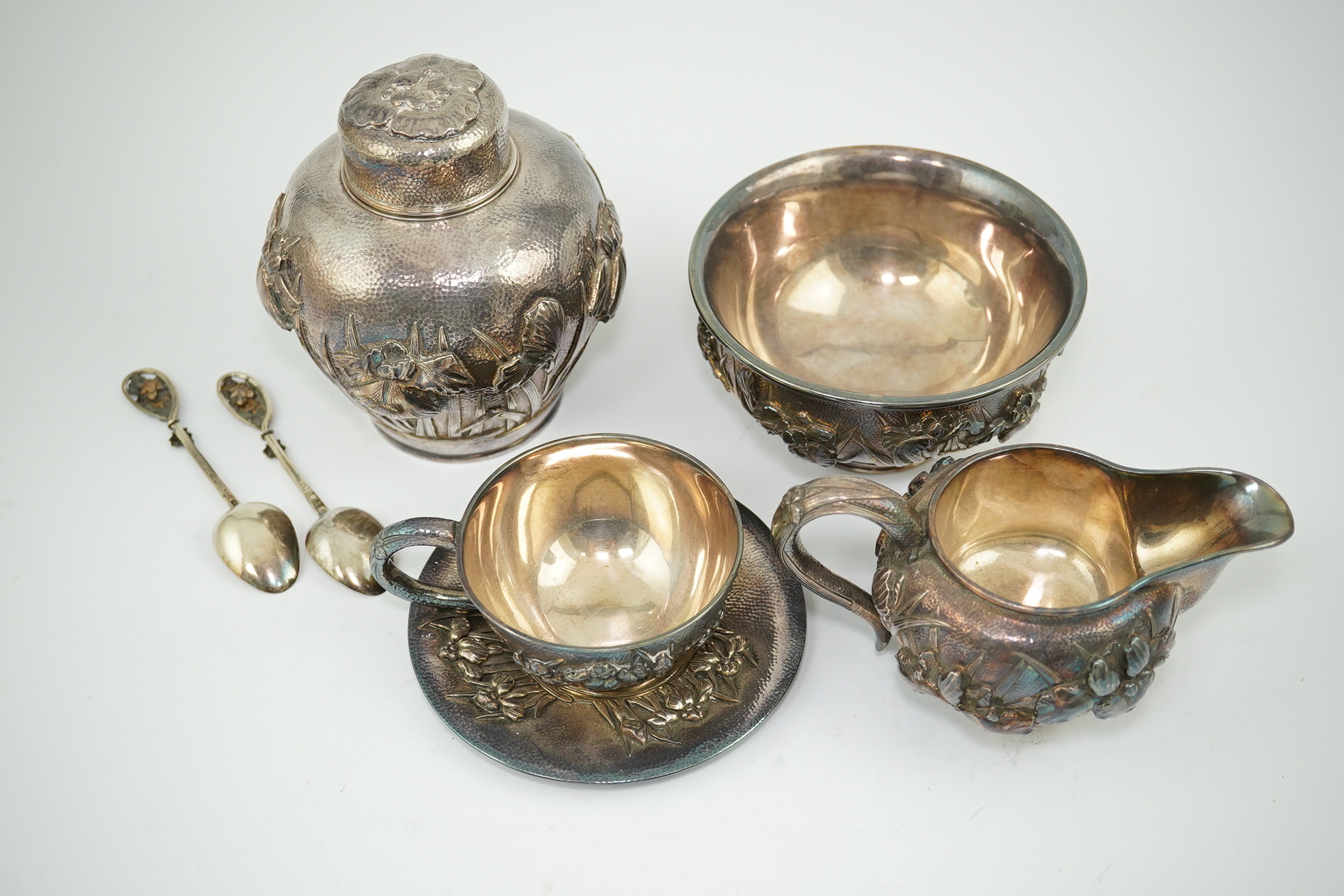 An early 20th century Japanese Meiji period planished silver matched? part tea set comprising a tea caddy with covers, sugar bowl, cream jug and tea cup and saucer